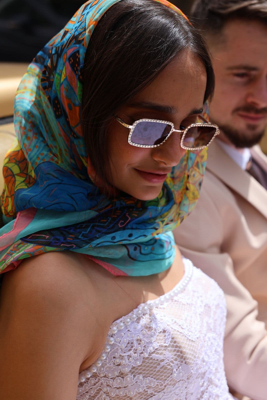 A bride in a vivid silk headscarf and jewelled sunglasses