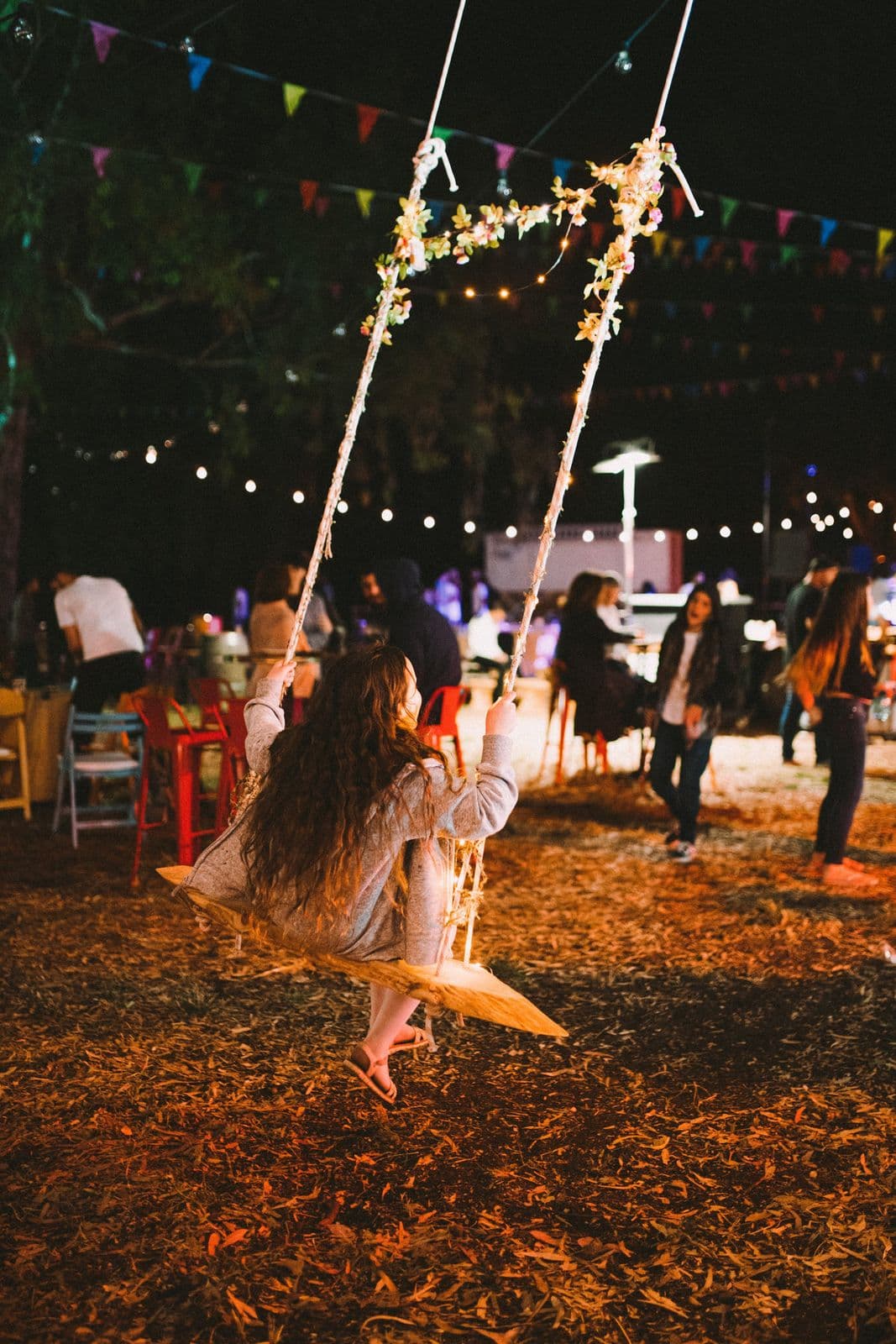 A guest on a swing beneath fairy lights at an evening wedding party